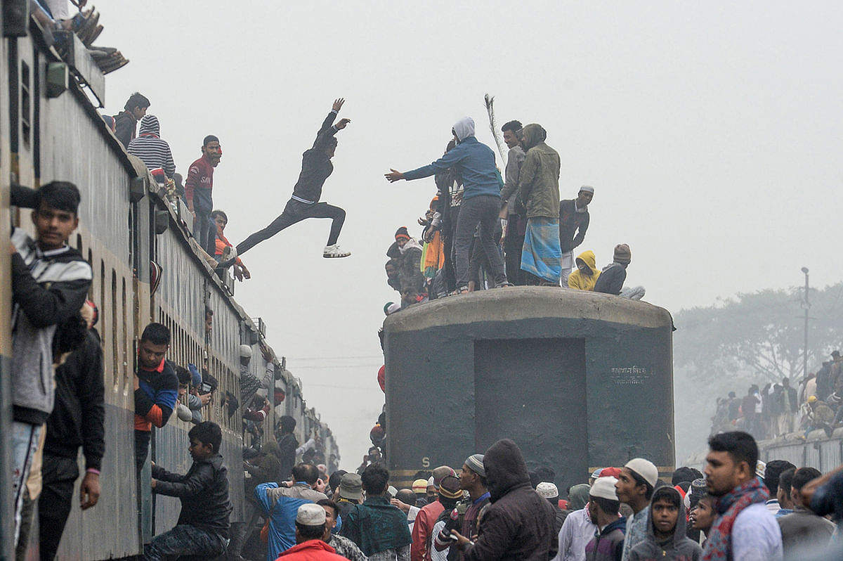 A Muslim devotee (C) jumps on to another train as he arrives along with others to take part in the Akheri Munajat, or final prayers, during the annual Muslim gathering `Biswa Ijtema` in Tongi, some 30 kms north of Dhaka on 12 January, 2020. Photo: AFP