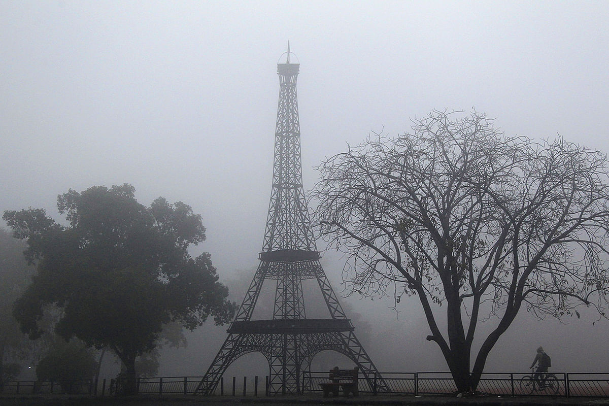 A man cycles past a replica of the Eiffel Tower in a park amid dense fog on a cold winter morning in Chandigarh on 14 January, 2020. Photo: AFP