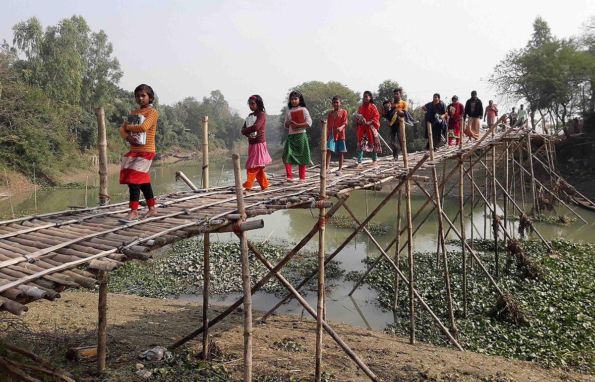 Risking their lives, schoolchildren cross a bamboo bridge over the Sonaidanga river in Singra upazila of Natore on 14 January 2020. Photo: Mukter Hossain