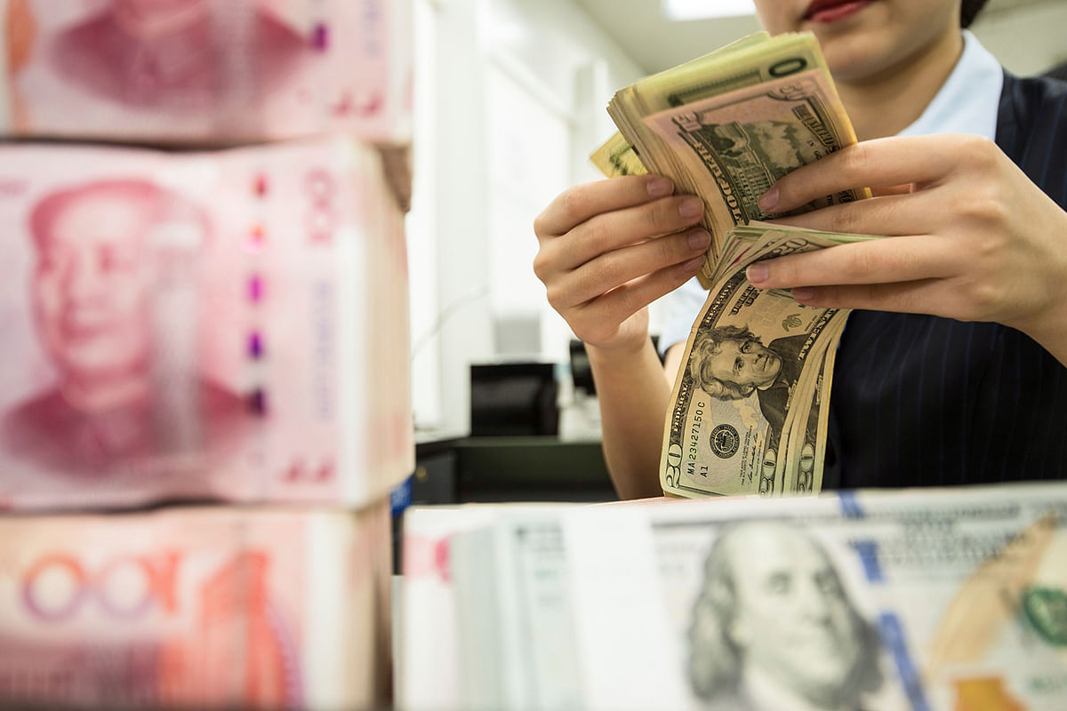 In this file photo taken on 5 August 2019 a Chinese bank employee counts 100-yuan notes and US dollar bills at a bank counter in Nantong in China`s eastern Jiangsu province. Photo: AFP