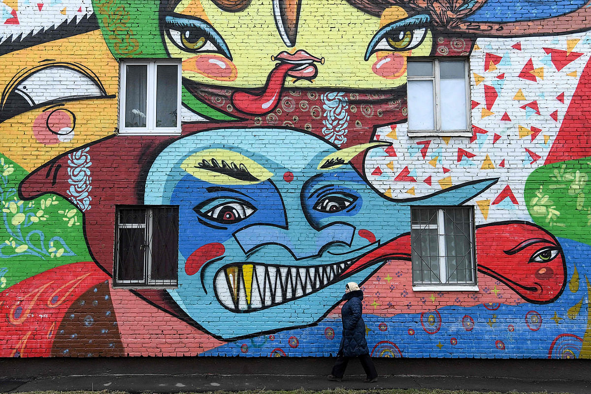 A woman walks past an apartment building with its wall covered with the graffiti by Russia`s graffiti group Influx crew in the Moscow suburb on 14 January 2020. Photo: AFP