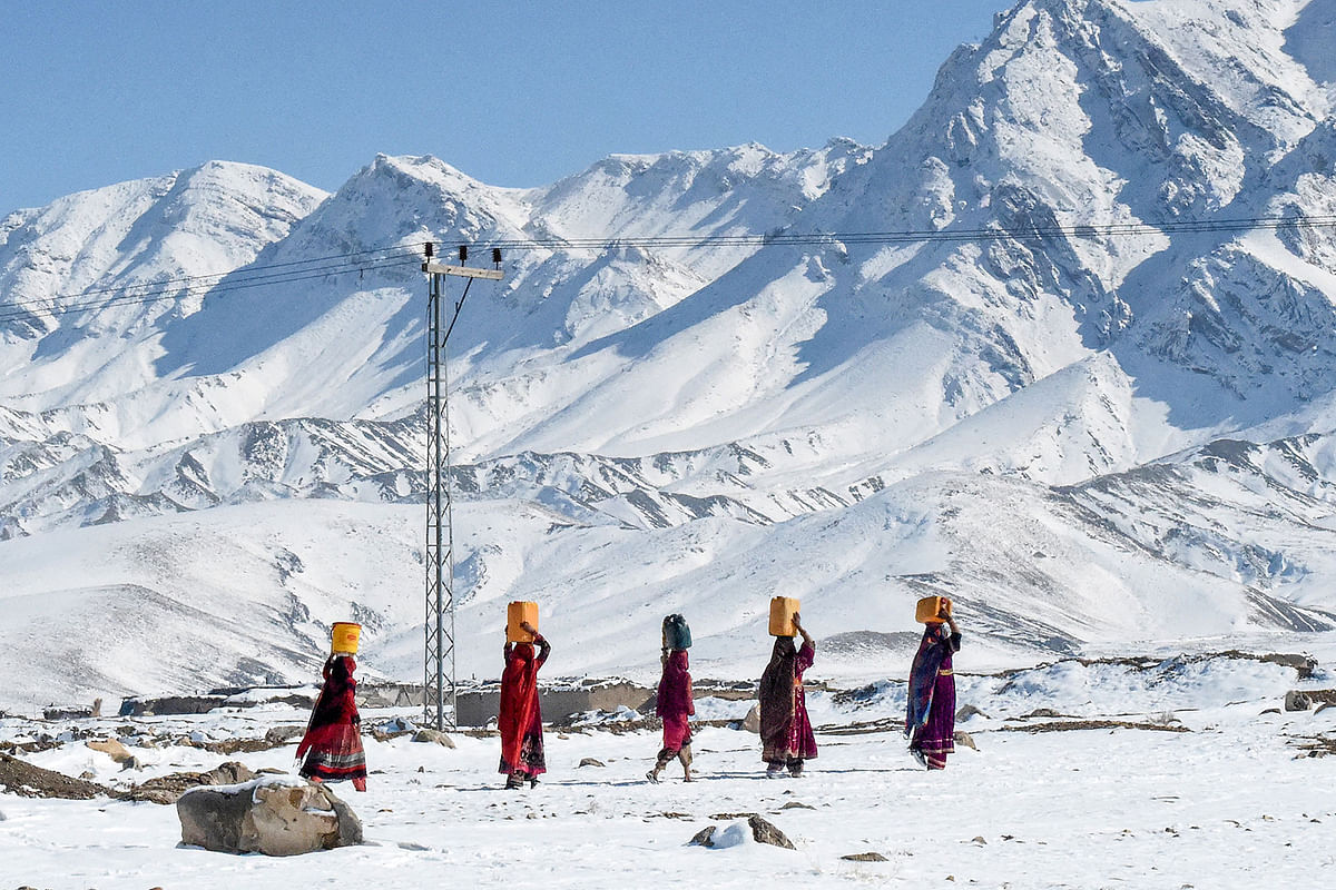 Local residents carry water pots above their heads as they walk back to their homes after heavy snowfall in Khanozai area some 75 kms in northeast of the provincial capital Quetta on 14 January 2020. Photo: AFP