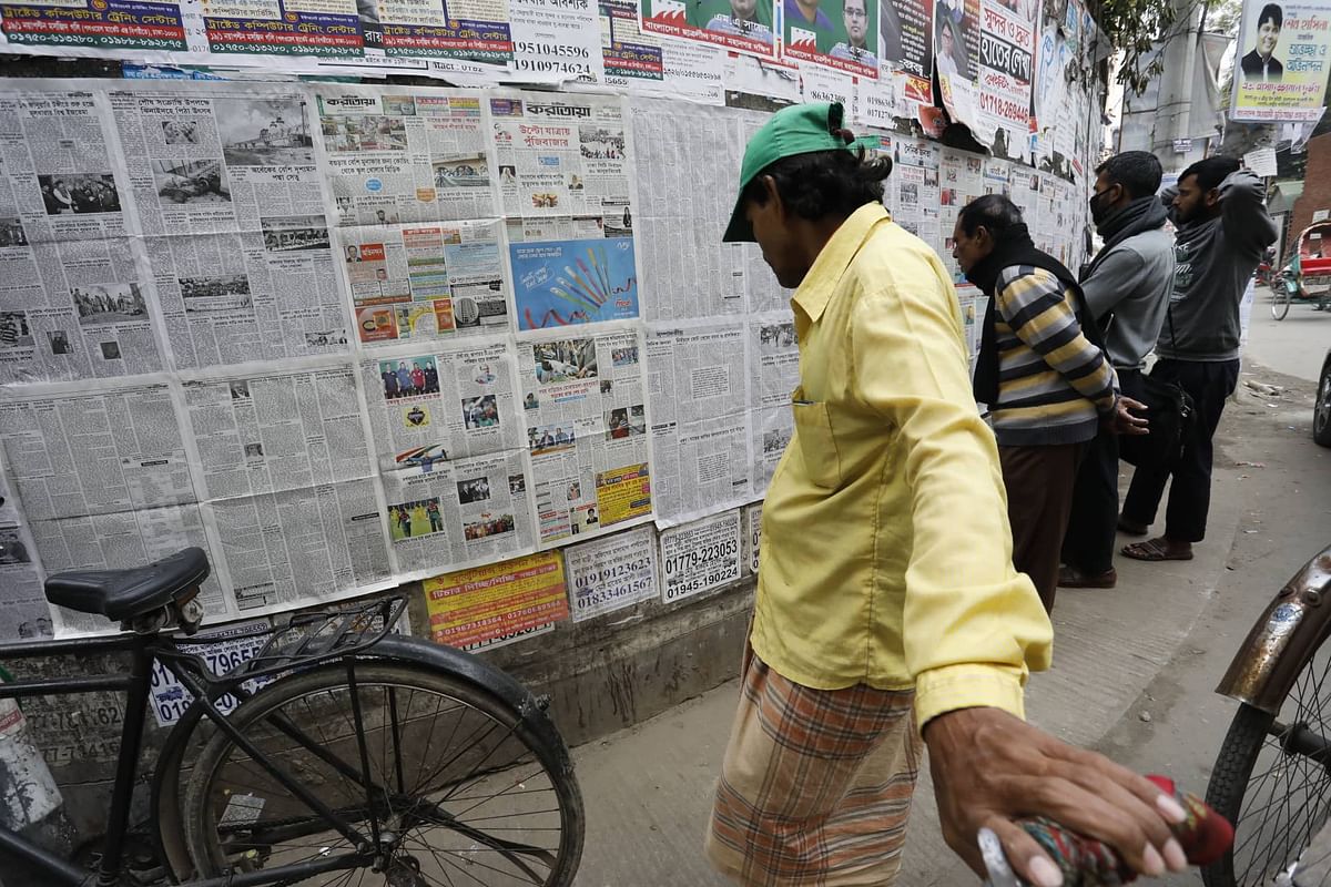 People read newspapers pasted on the wall at Topkhana Road, Dhaka on 15 January 2020. Photo: Dipu Malakar