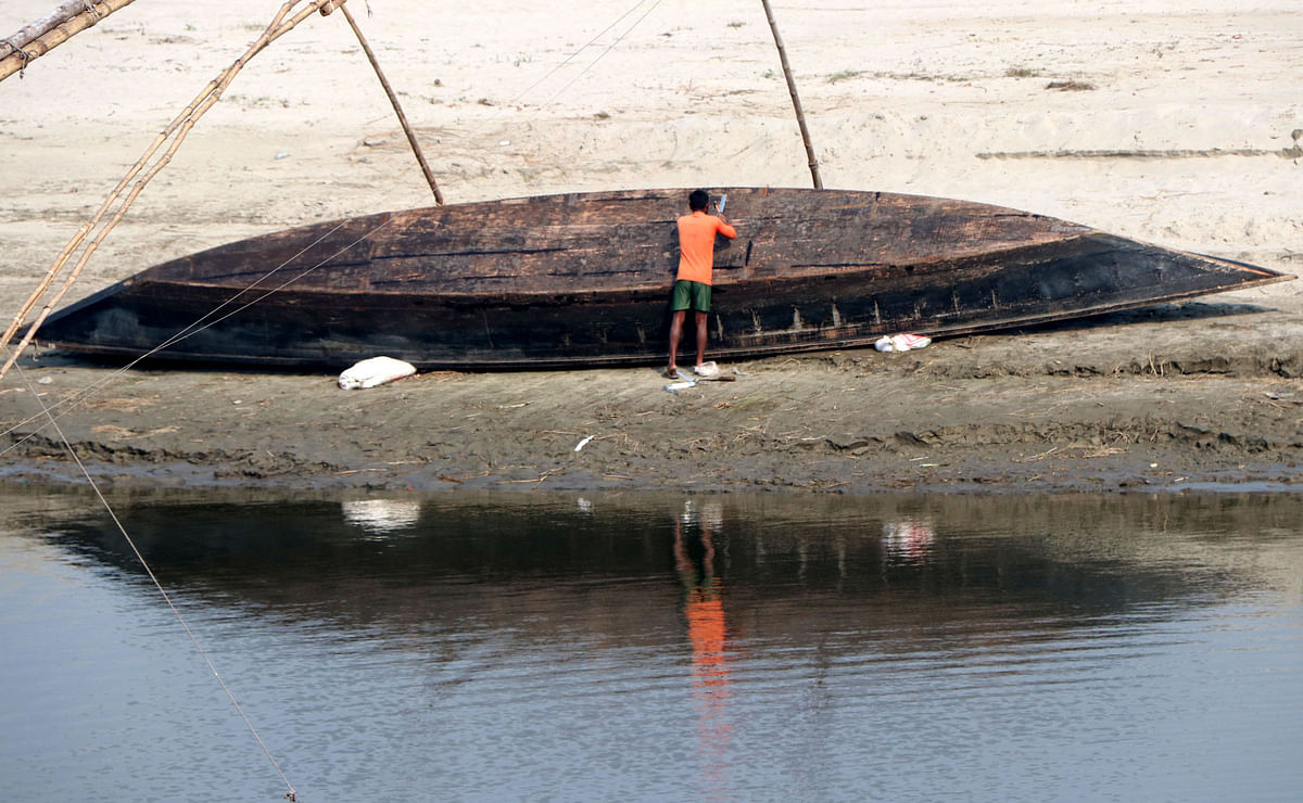 A man overturns a boat in the winter at Dholirkandi, Sariakandi, Bogura on 15 January 2020. Photo: Soel Rana