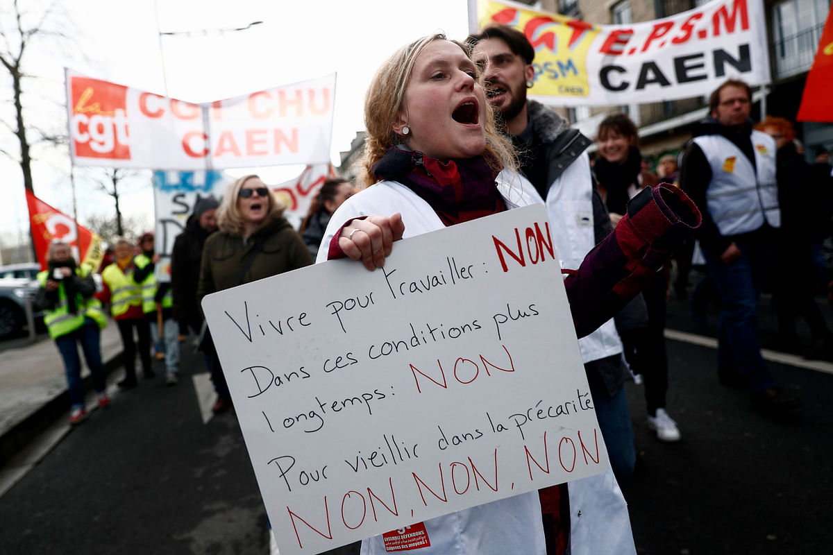 A demonstrator holds a placard reading `To live to work: NO! In those conditions anymore: NO! To grow old in precarious conditions: NO`` during a demonstration in Caen, northern France, on 16 January 2020, as part of a nationwide multi-sector strike against the French government`s pensions overhaul. Unions have been waging a transport strike against the pension overhaul since 5 December, the longest transport strike in France in decades. Photo: AFP