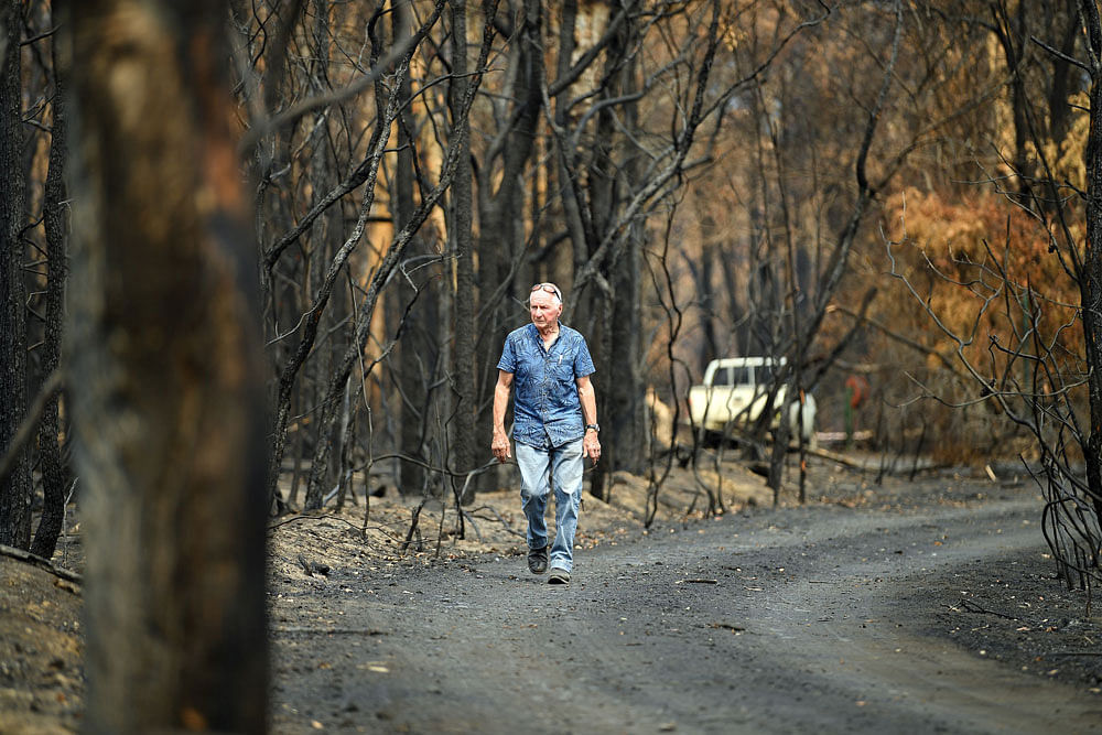 This photo taken on 15 January, 2020 shows environmentalist Ken Stewart walking down the street from his burnt house following the bushfire in Budgong area of New South Wales. Photo: AFP