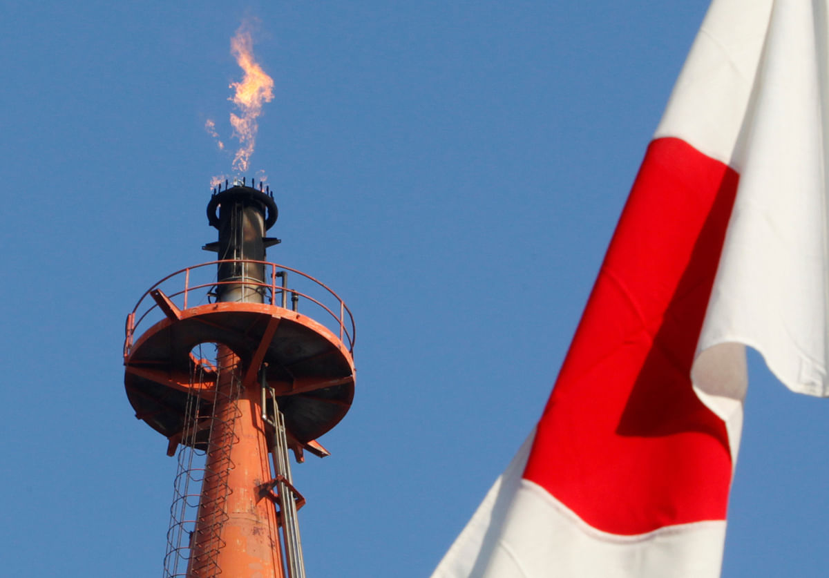 A Japanese national flag flutters near a flare from a chimney at a steel plant at Keihin industrial zone in Kawasaki, south of Tokyo on 21 January 2011. Reuters File Photo