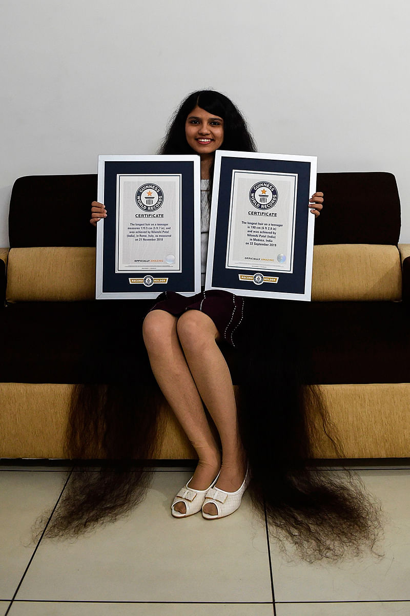 Nilanshi Patel, 17, poses for picture with the 2018 (L) and 2019 Guinness World Record certificates for the longest hair in the teenager category, at Modasa town, some 110 Kms from Ahmedabad on 19 January 2020. Photo: AFP