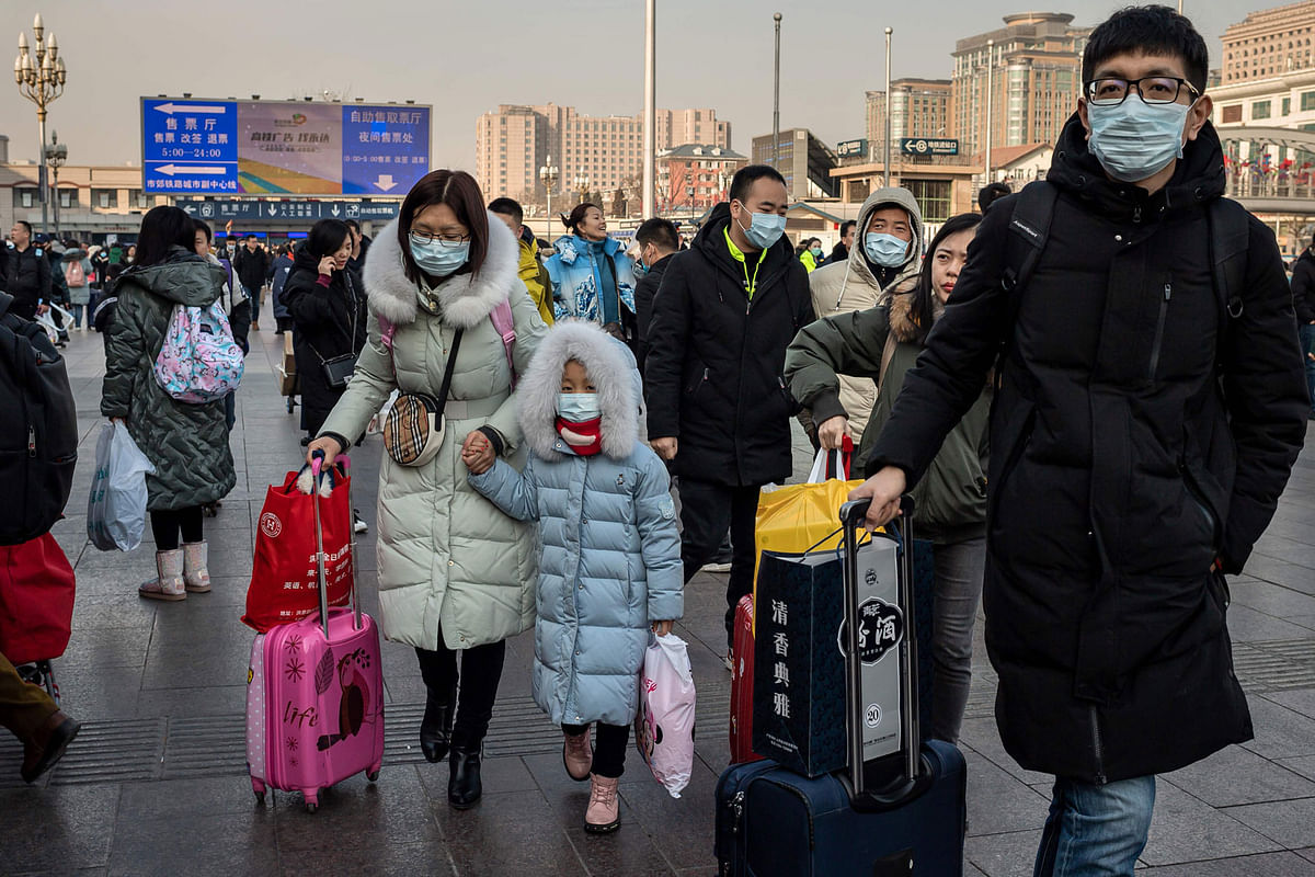 People wearing protective masks arrive at Beijing railway station to head home for the Lunar New Year on 21 January 2020. Photo: AFP