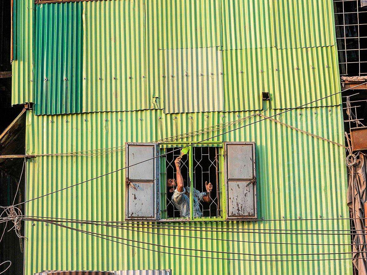 A man paints a window of a house near the Buriganga river in Dhaka on 21 January 2020. Bangladesh`s high court has ordered the shutdown of 231 factories that have contributed to Dhaka`s main river becoming one of the world`s most polluted, a lawyer said on 21 January. Photo: AFP