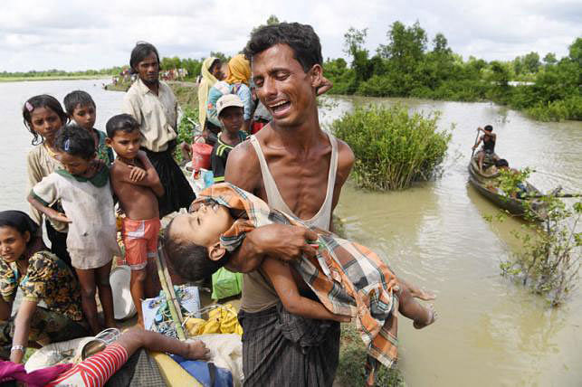 A Rohingya refugee reacts while holding his dead son after crossing the Naf river from Myanmar into Bangladesh in Whaikhyang on 9 October 2017. Photo: AFP