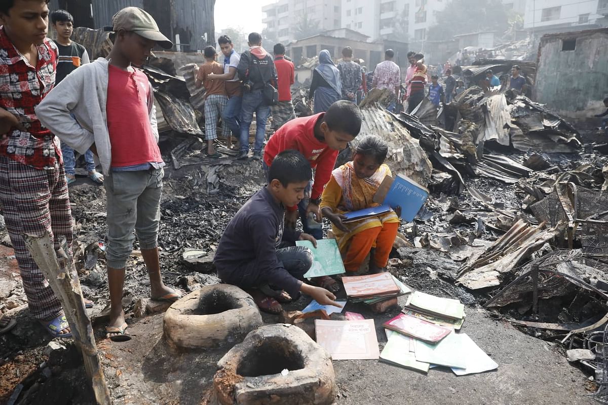 A boy tries to save his books from fire in a slum in Mirpur’s Chalantika on 24 January 2020. Photo: Prothom Alo