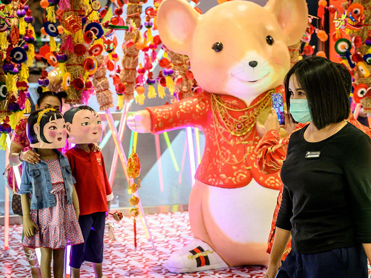 A woman with a face mask walks in a shop decorated for the Chinese Lunar New Year in Bangkok on 24 January 2020, after four people were detected with the Coronavirus in Thailand. Photo: AFP