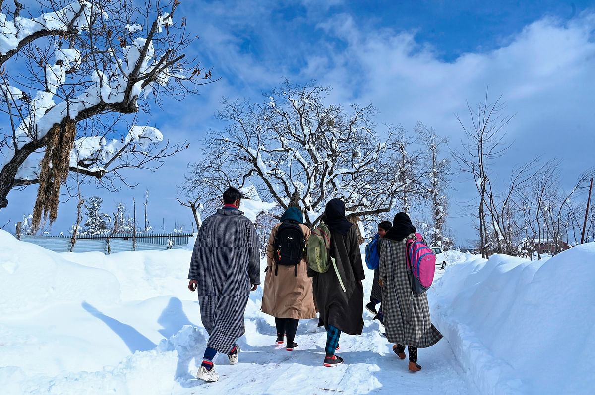 Students walk after a heavy snowfall at Kanidajan area of Budgam district in Srinagar on 18 January 2020. Photo: AFP