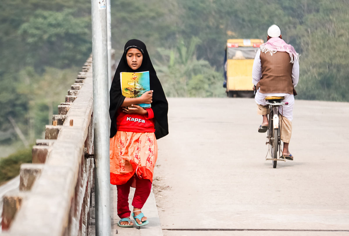 A girl walks on a bridge holding books at Charbaria, Barishal on 25 January 2020. Photo: Saiyan