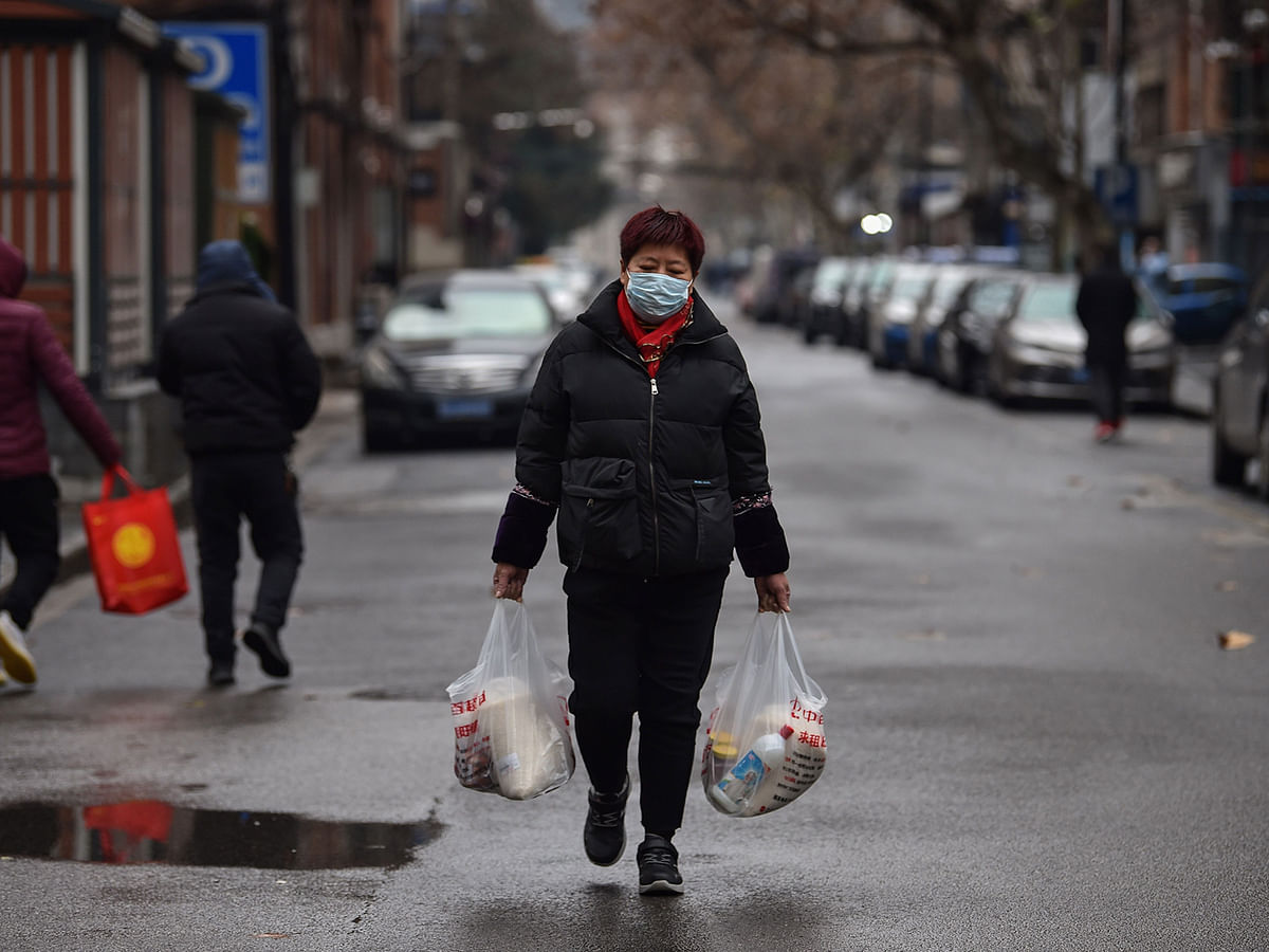 A woman wearing a protective facemask returns from a market in Wuhan on January 26, 2020, a city at the epicentre of a viral outbreak that has killed at least 56 people and infected nearly 2,000. China on 26 January expanded drastic travel restrictions to contain the viral contagion, as the United States and France prepared to evacuate their citizens from the quarantined city at the outbreak`s epicentre. Photo: AFP