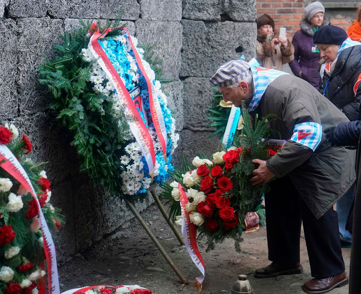 A Holocaust survivor places flowers at the death wall at the memorial site of the former German Nazi death camp Auschwitz during ceremonies to commemorate the 75th anniversary of the camp`s liberation in Oswiecim, Poland, on 27 January 2020. Photo: AFP