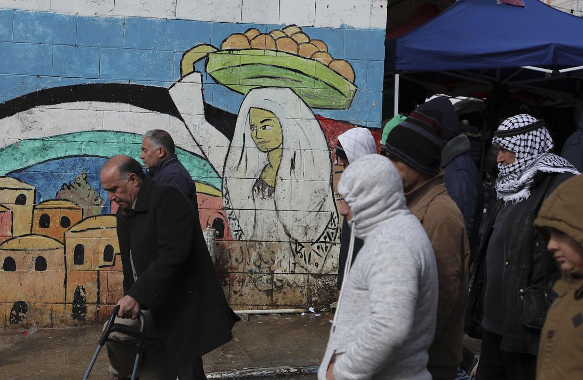 Palestinians walk past a mural painting in Ramallah in the occupied West Bank on 24 January. Photo: AFP