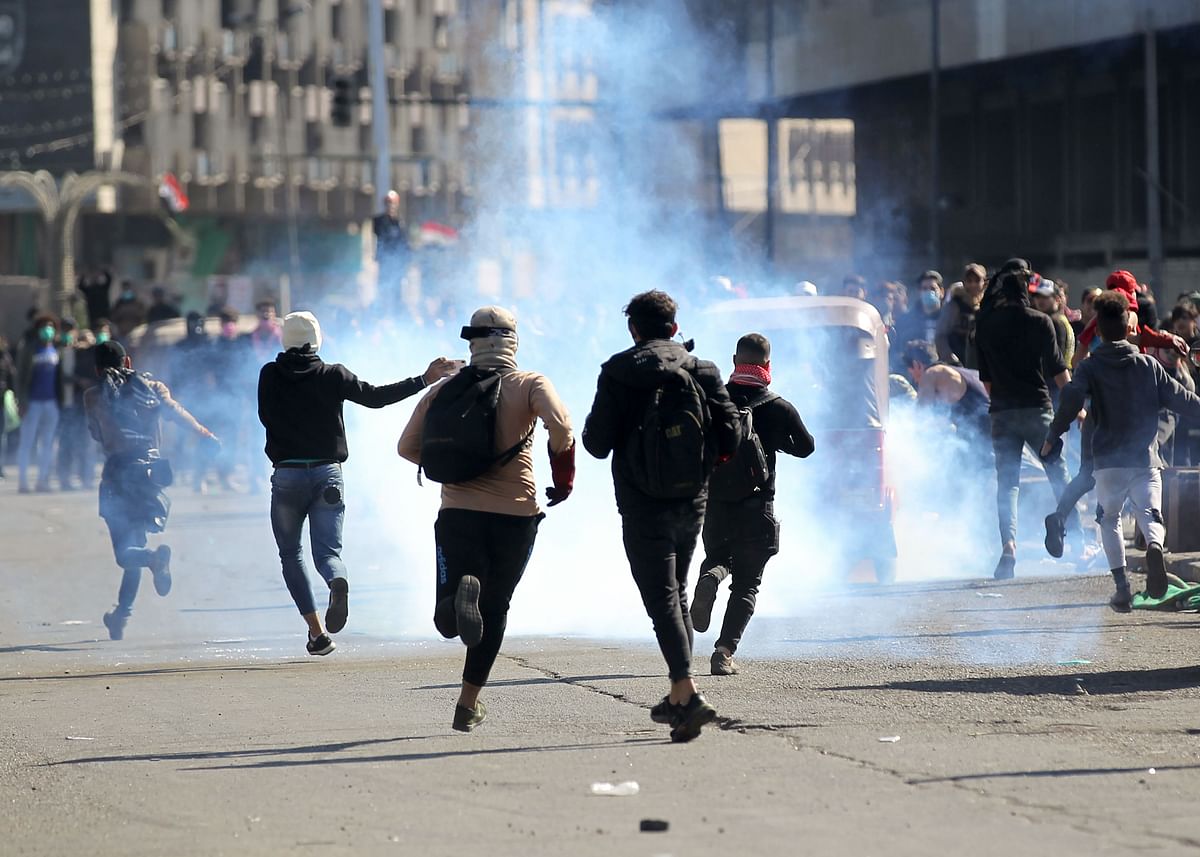 Iraqi protesters rush to catch a tear gas canisters fired by security forces during clashes following an anti-government demonstration in Al-Khilani square in the capital Baghdad, on 26 January. Photo: AFP