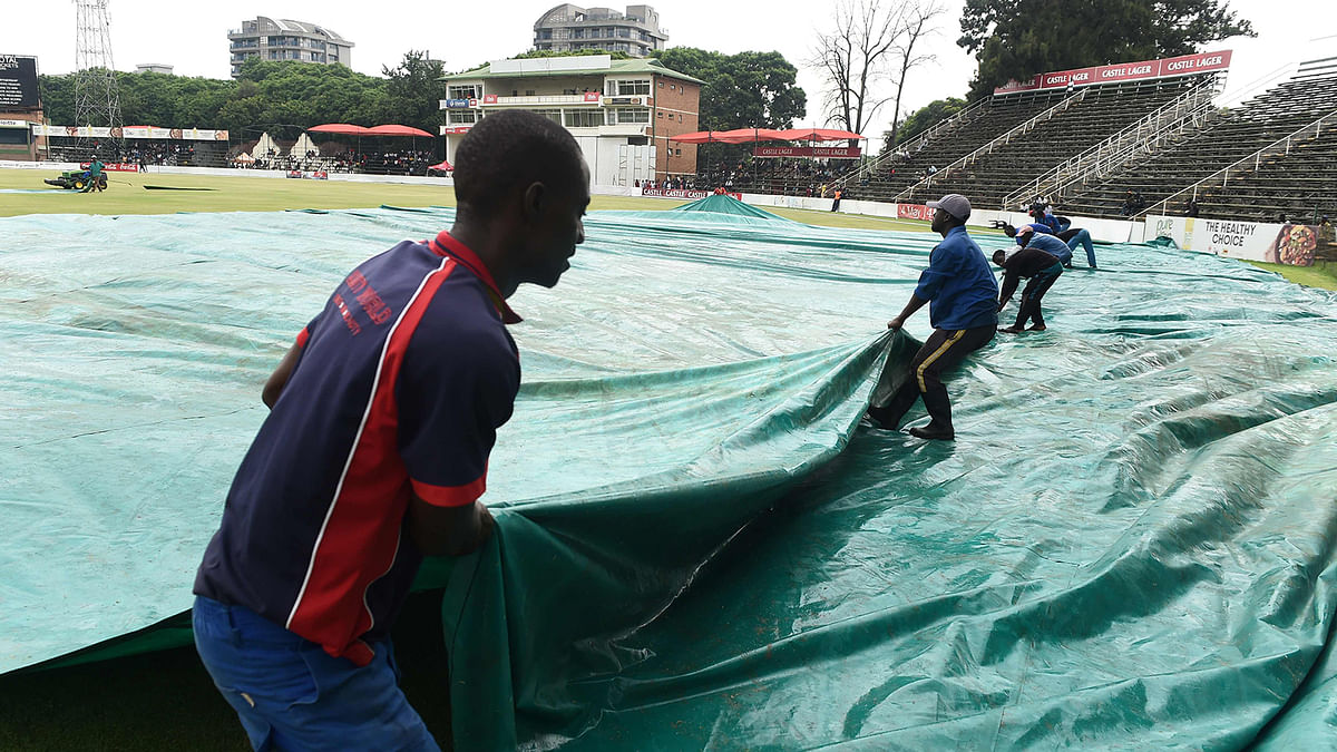 Groundsmen drag a sail onto the field to cover the pitch as rain has delayed play during the fourth day of the second Test cricket match between Zimbabwe and Sri Lanka at the Harare Sports Club in Harare on 30 January 2020. Photo: AFP