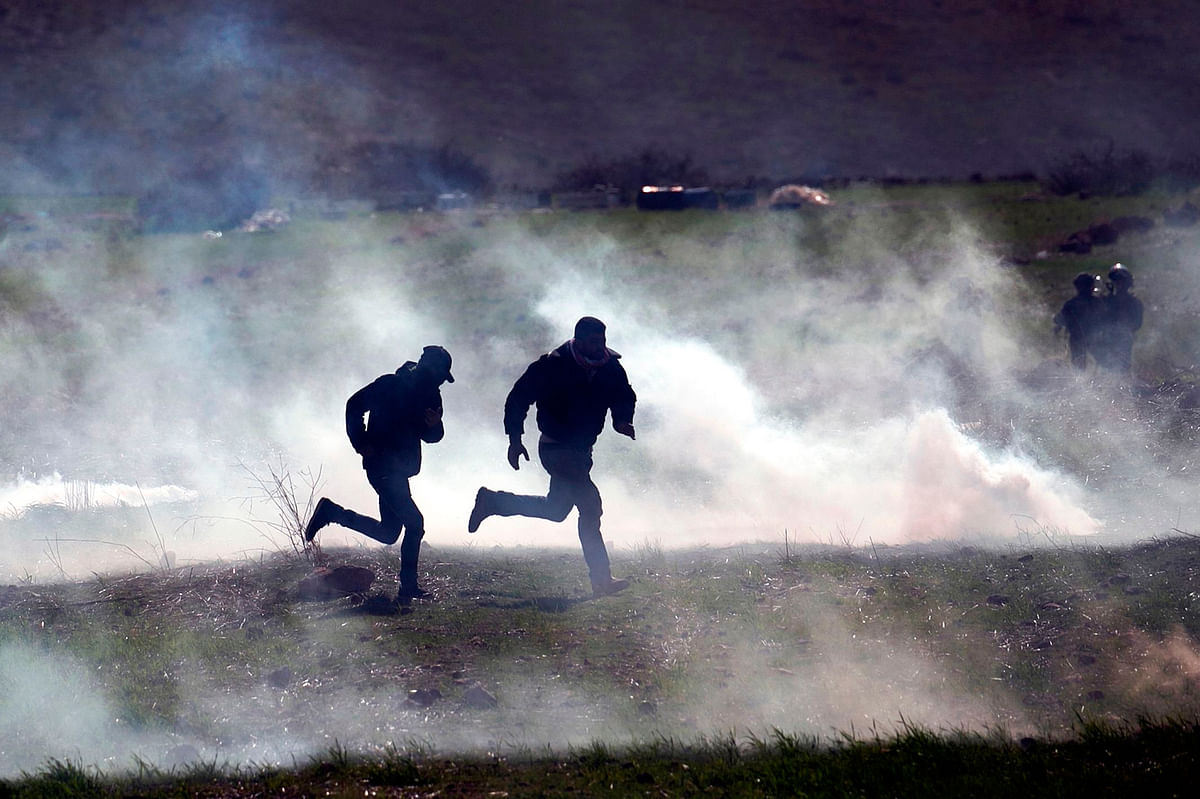 Palestinian protesters run for cover amid clashes with Israeli troops during a demonstration against a US brokered Middle East peace deal, near the West Bank village of Tamun near the Jordan Valley on 31 January, 2020. Photo: AFP
