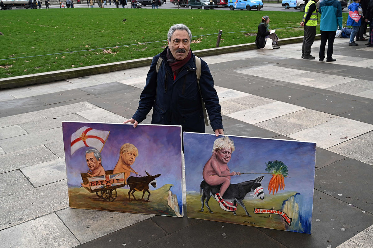 A man holds paintings depicting Britain`s Prime Minister Boris Johnson (R) and former leader of the UK Independence Party Nigel Farage (L) at Parliament Square near the Houses of Parliament in London on 31 January, 2020 on the day that the UK formally leaves the European Union. Photo: AFP