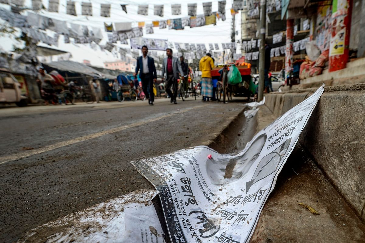 In this photograph taken on 29 January 2020, people walk on a street adorned with election posters laminated with plastic in Dhaka. Dhaka is awash with an estimated 304 million plastic-laminated posters ahead of elections in the Bangladeshi capital, and environmentalists are up in arms. Photo: AFP
