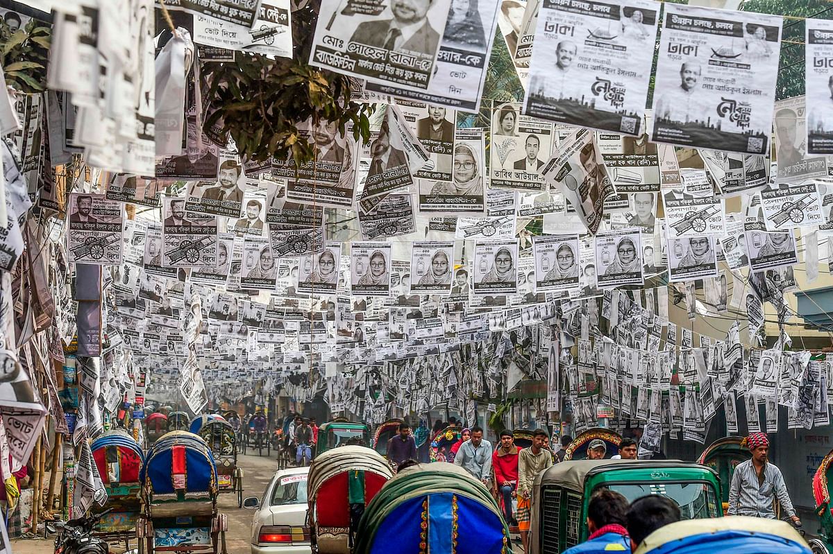 In this photograph taken on 29 January 2020, commuters make their way on a street adorned with election posters laminated with plastic in Dhaka. Photo: AFP