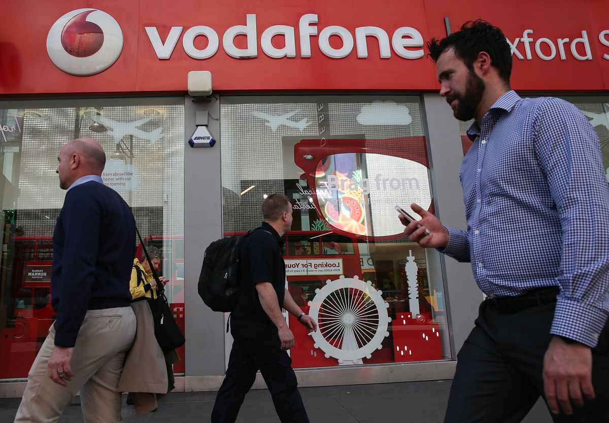 In this file photo taken on 16 May 2017 A man uses a smartphone as he walks past a Vodafone store in central London on 16 May 2017. Photo: AFP