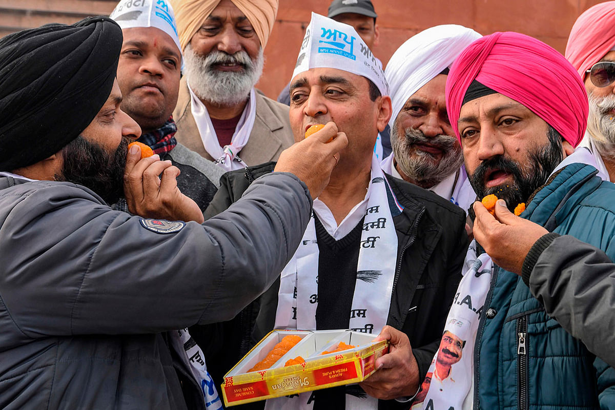 Aam Aadmi Party (AAP) workers offer sweets to each other as they celebrate victory following the early results of New Delhi regional assembly election, in Amritsar on 11 February 2020. Photo: AFP