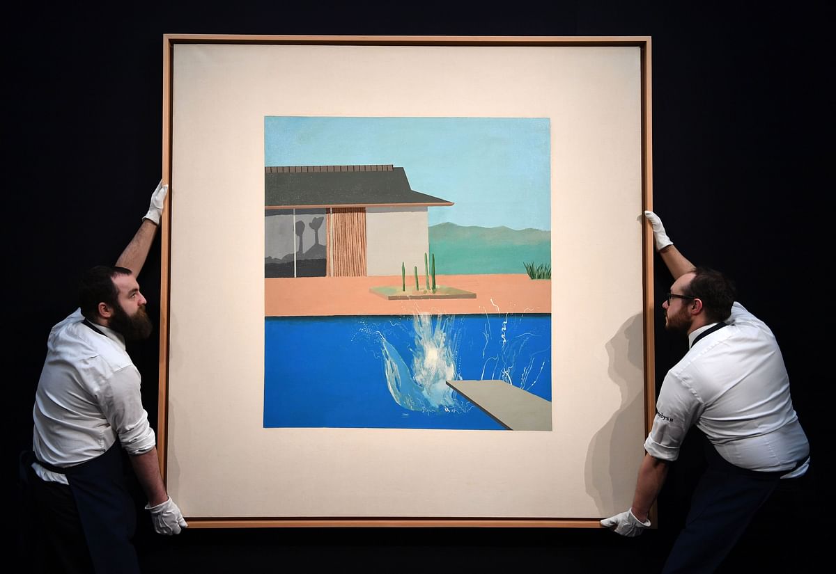 In this file photo taken on 7 February gallery assistants are pictured posing next to an artwork entitled `The Splash` 1966, by British artist David Hockney, during a photo call at Sotheby`s Galleries in central London. Photo: AFP