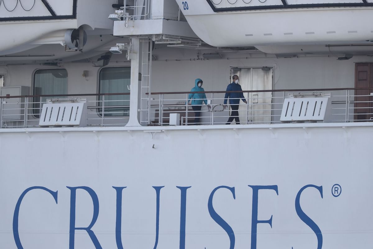 Passengers wearing face masks walk on the Diamond Princess cruise ship, with around 3,600 people quarantined onboard due to fears of the new coronavirus, at the Daikaku Pier Cruise Terminal in Yokohama port on 12 February 2020. Photo: AFP