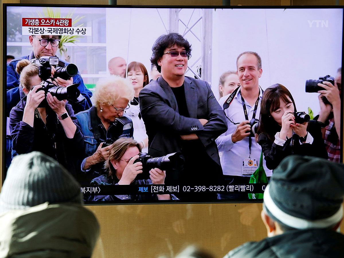 People watch a TV broadcasting a news report on South Korean director Bong Joon-ho who won four Oscars with his film `Parasite`, in Seoul, South Korea on 10 February. Photo: Reuters
