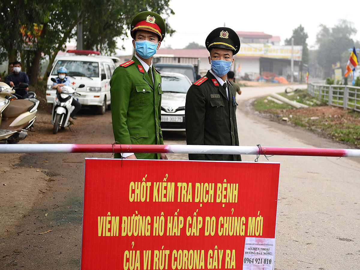 Vietnamese police wearing protective facemasks amid concerns of the COVID-19 coronavirus outbreak stand guard at a checkpoint in Son Loi commune in Vinh Phuc province on 13 February 2020. Photo: AFP
