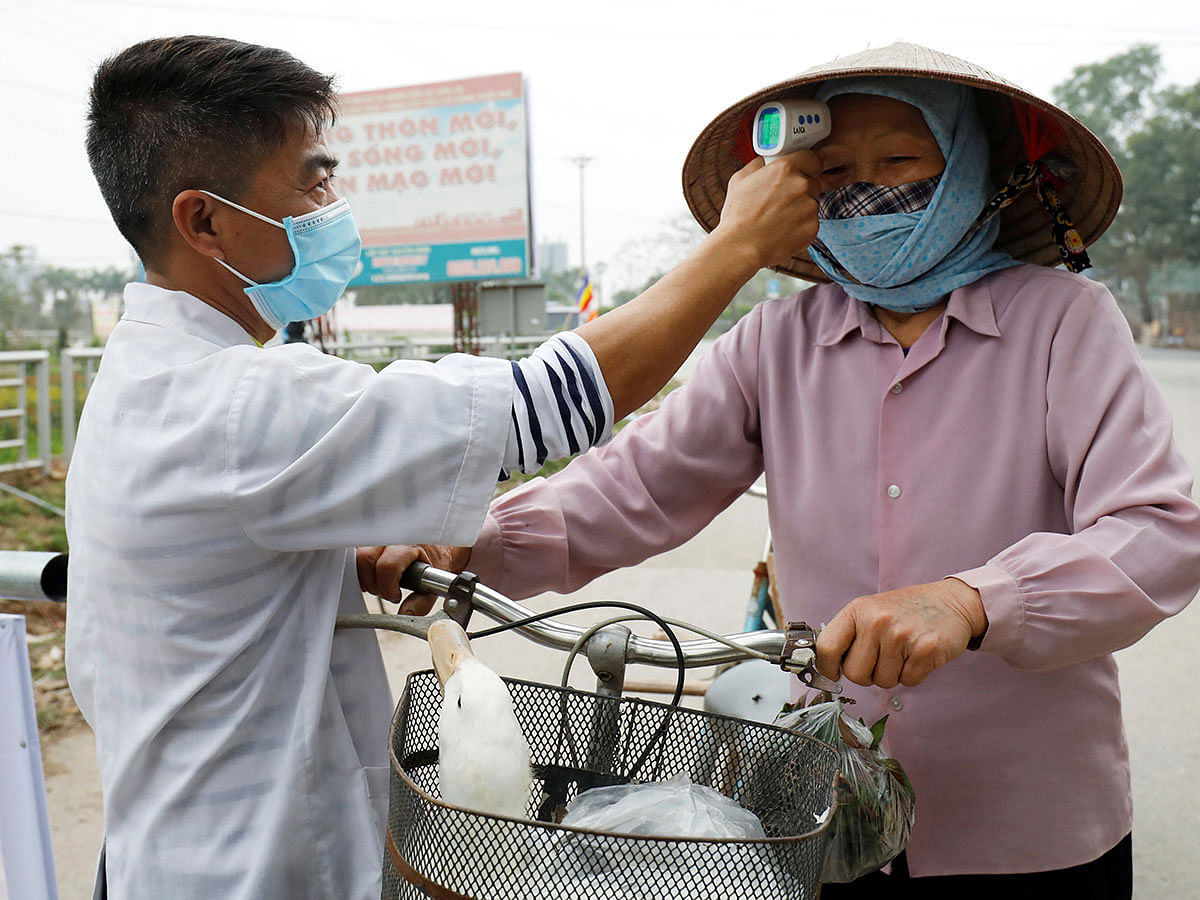 A Vietnamese health worker checks a farmer`s temperature at a check point of a village in Vinh Phuc province, Vietnam on 12 February 2020. Photo: Reuters