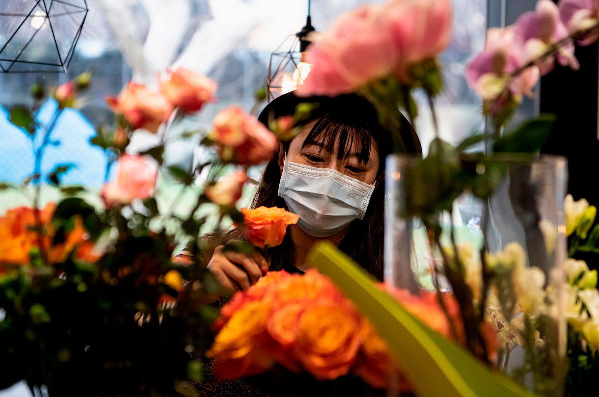 This photo taken 2020 shows florist Zhao Yuanyuan wearing a protective face mask as she arranges flowers in her shop in Shanghai ahead of Valentine`s Day. Couples around China are settling for a quiet Valentine`s Day this year, with the deadly COVID-19 coronavirus as an unwelcome third-wheel in romantic celebrations. Photo: AFP