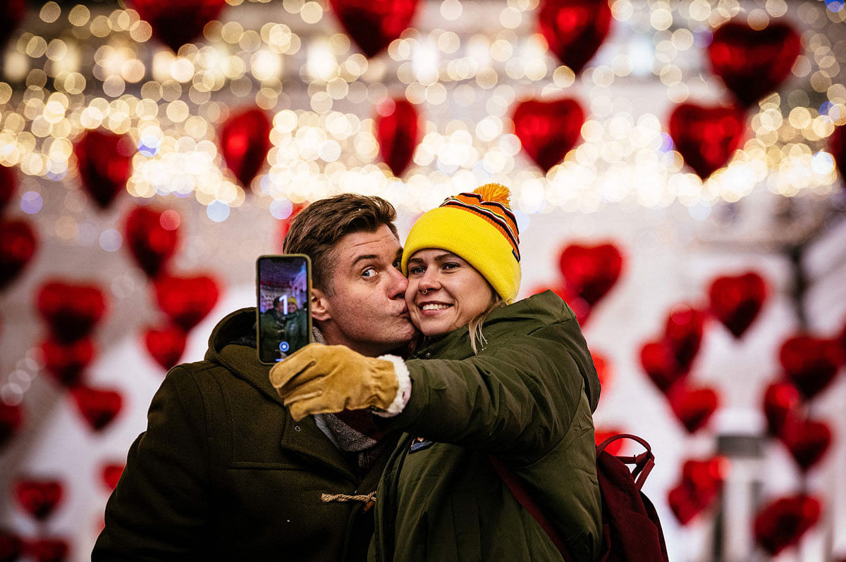 A couple kisses as they pose for a selfie under heart-shaped balloons displayed on the eve of Valentine`s Day in downtown Moscow on 13 February 2020. Photo: AFP