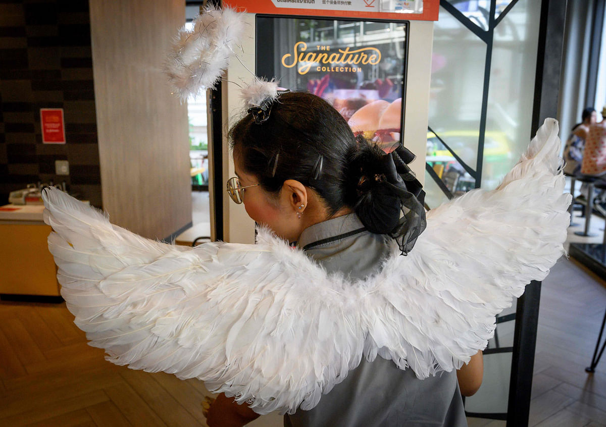 An employee of a fast food chain wears angel wings to celebrate Valentine`s Day in Bangkok on 14 February 2020. Photo: AFP