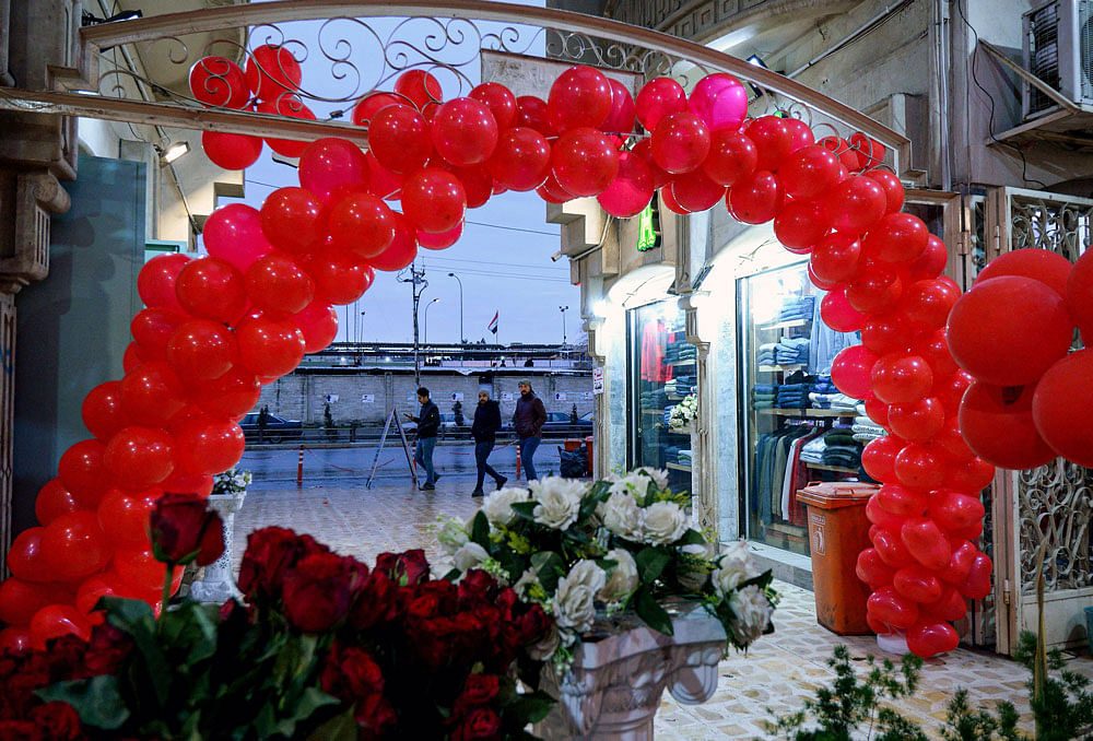 Men walk past the entrance of a shopping mall in Iraq`s northern city of Mosul, decorated with flowers and red balloons ahead of Valentine`s day. Photo: AFP