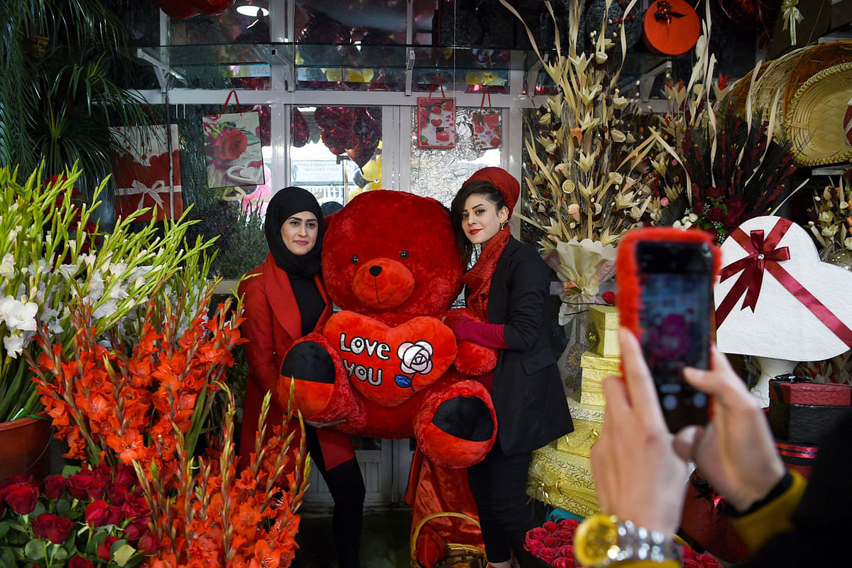 Two women working for Afghan Mitra TV pose wiht a doll on Valentine`s Day in Kabul. Photo: AFP