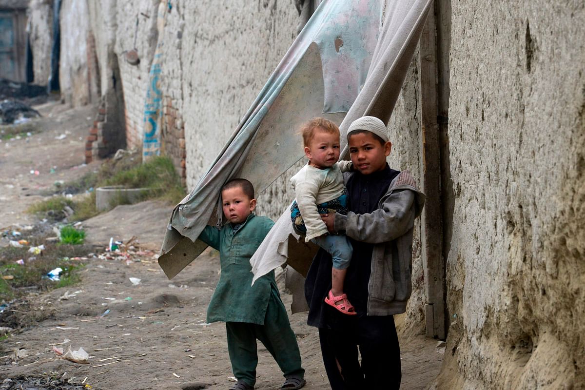 In this picture taken on 12 February 2020, Afghan refugee children stand in front of their home in a refugee camp in Peshawar. Photo: AFP