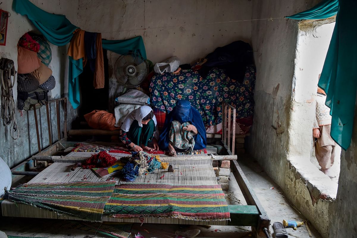 In this picture taken on 12 February 2020, Afghan refugee women make carpet at their home in a refugee camp in Peshawar. Photo: AFP