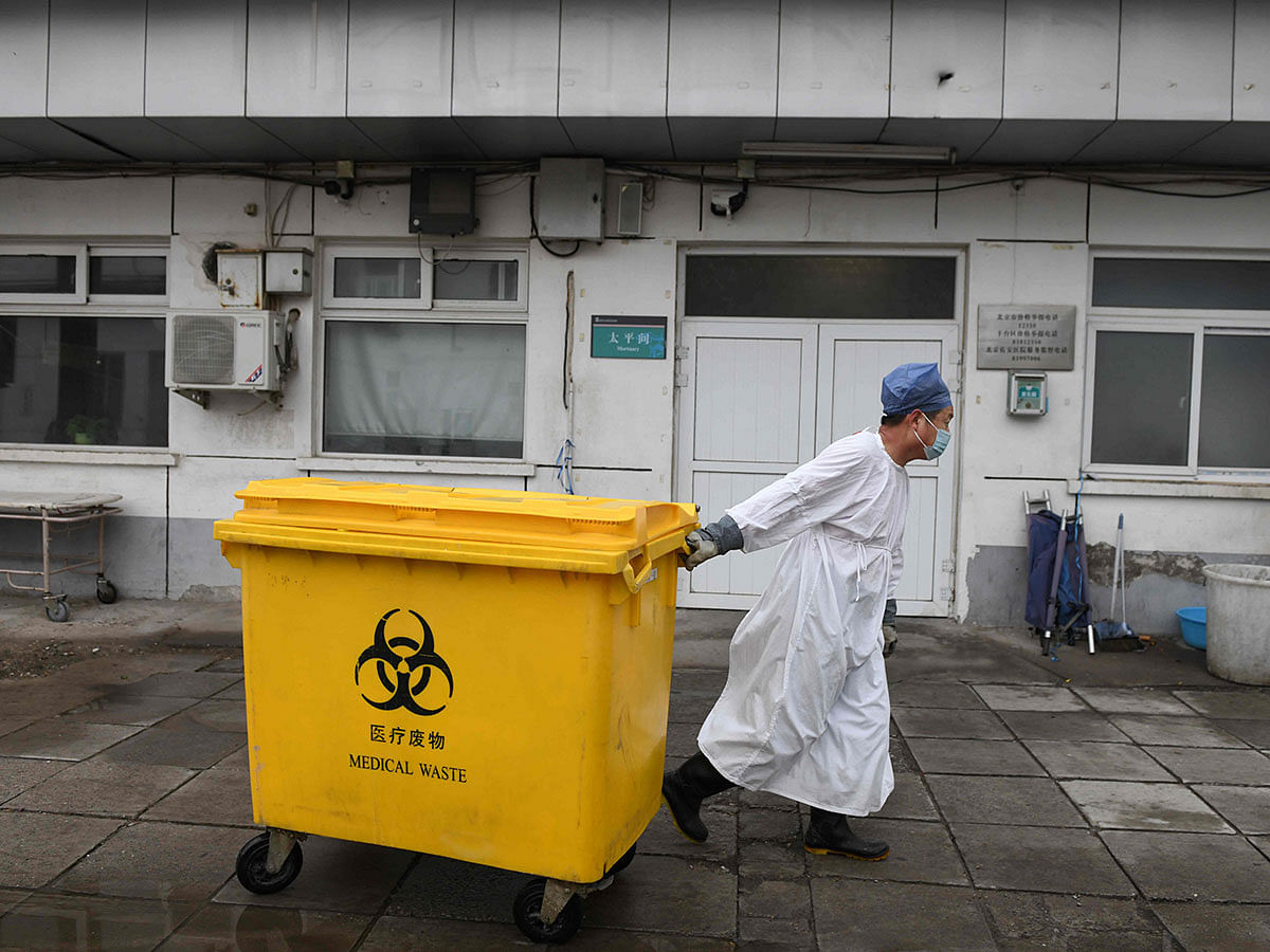 A worker carts a bin loaded with medical waste past the mortuary, to a storage facility at the Youan Hospital in Beijing on 14 February 2020. Photo: AFP
