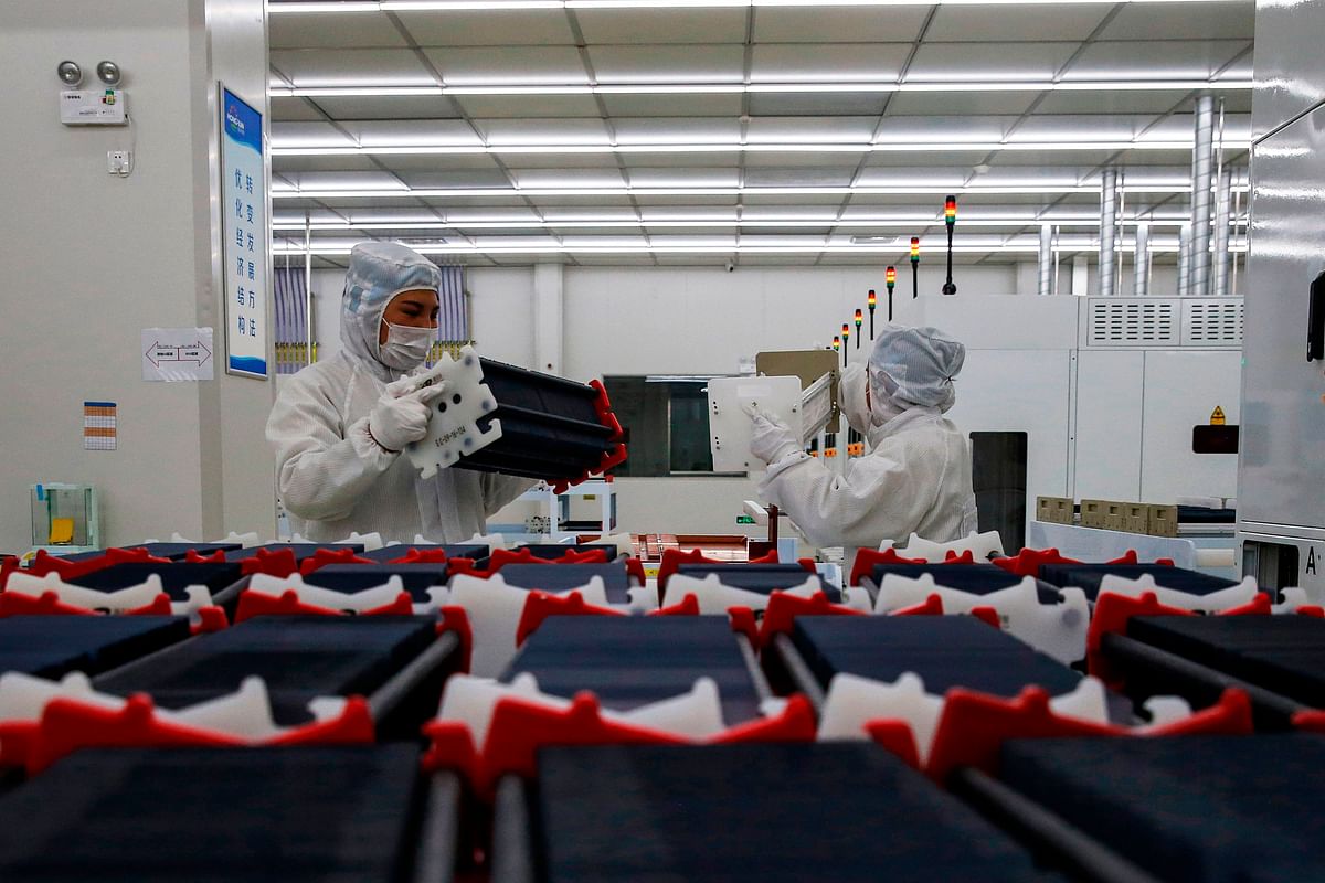 This photo taken on 16 February, 2020 shows Chinese employees wearing face masks and protective suits working on a smart chip production line in Sihong in China`s eastern Jiangsu province. Photo: AFP