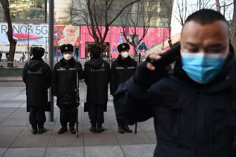 Security guards wearing protective face masks, amid concerns of the COVID-19 coronavirus outbreak, patrol in a shopping area in Beijing on 17 February 2020. Photo: AFP