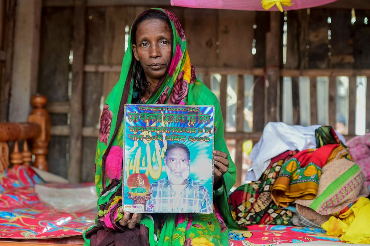 In this photograph taken on 11 November, 2019, Bangladeshi mother-of-four Mosammat Rashida, whose husband was killed by a Bengal tiger a decade ago while he was collecting honey, holds a portrait of her husband during an interview with AFP at her house in Shyamnagar. Photo: AFP