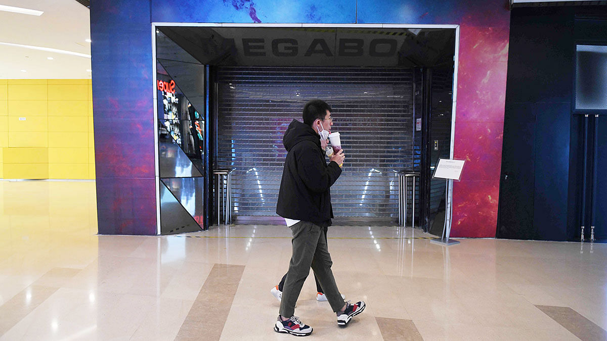 This photo taken on 16 February, 2020 shows a couple walking past the closed Megabox cinema in Beijing. Like entertainments across the capital, the eight-screen Megabox movie theatre has been closed for nearly a month in response to the COVID-19 coronavirus outbreak which has swept China, infecting more than 70,000 people. Photo: AFP