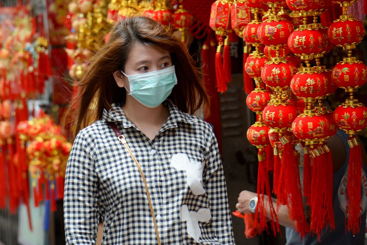 This photo taken on 14 February 2020 shows a woman wearing a face mask walking past a charms shop in the Binondo district of Chinatown in Manila. Photo: AFP