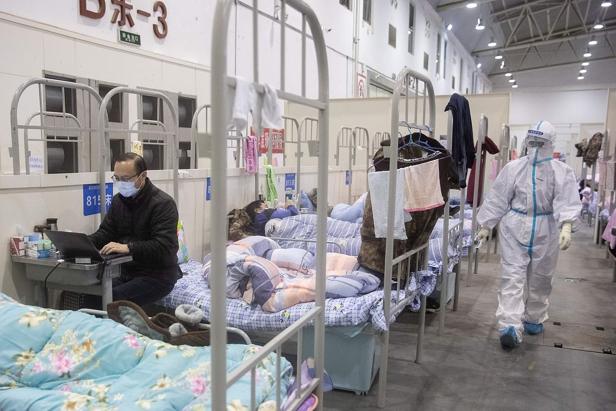 This photo taken on 17 February, 2020 shows a man (L) who has displayed mild symptoms of the COVID-19 coronavirus using a laptop at an exhibition centre converted into a hospital in Wuhan in China`s central Hubei province. Photo: AFP