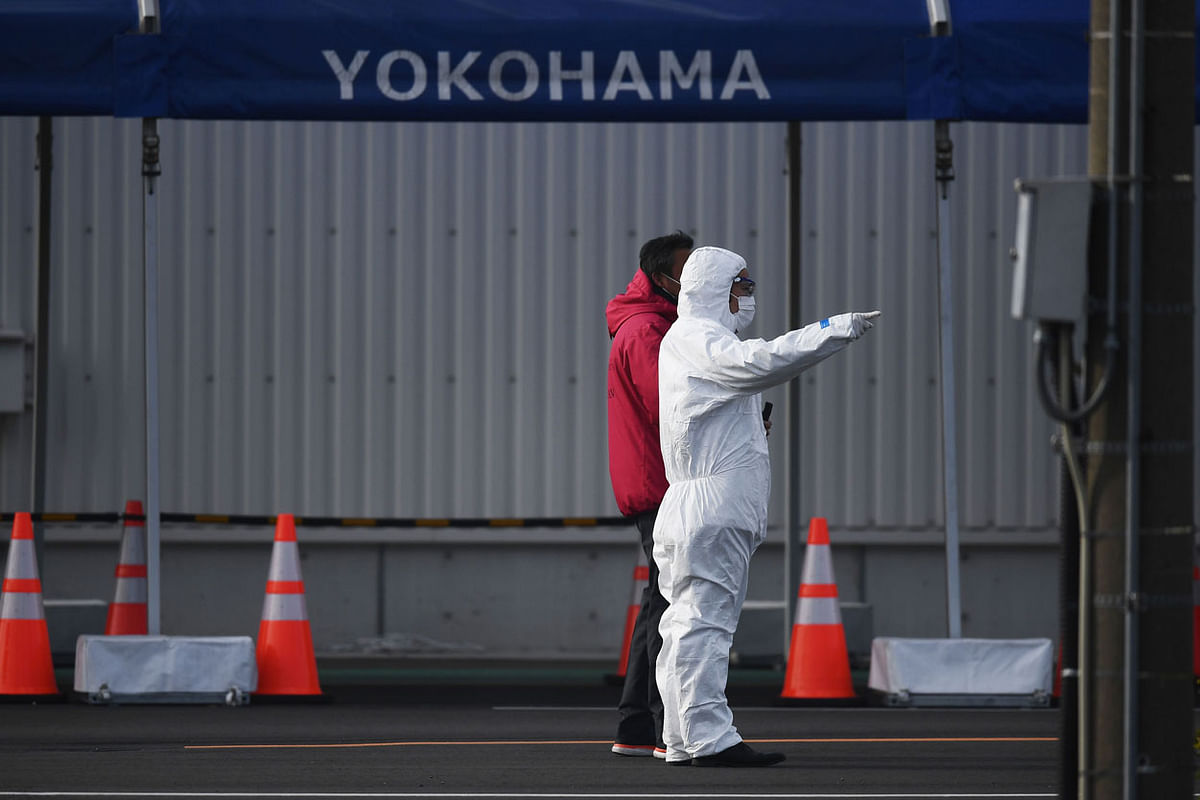 A man in protective gear is seen dockside next to the Diamond Princess cruise ship in quarantine due to fears of the new COVID-19 coronavirus, at the Daikoku Pier Cruise Terminal in Yokohama on 19 February. Photo: AFP